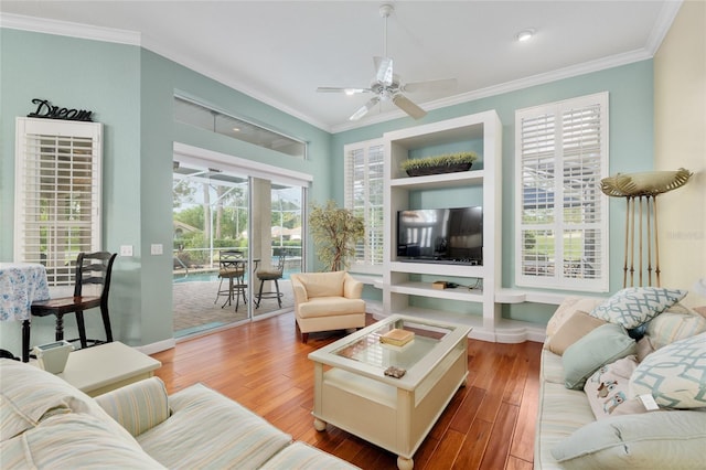 living area featuring wood finished floors, a ceiling fan, crown molding, and baseboards