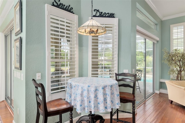 dining area with a chandelier, baseboards, wood finished floors, and crown molding
