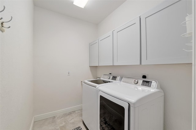 washroom featuring independent washer and dryer, cabinet space, and baseboards