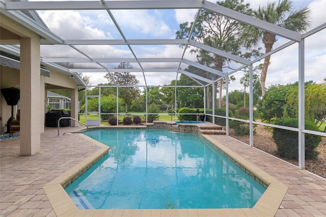 view of pool with a patio, glass enclosure, and a pool with connected hot tub