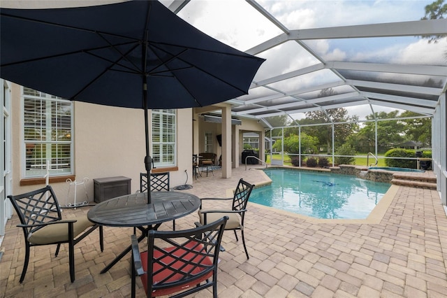 view of pool with outdoor dining area, glass enclosure, a pool with connected hot tub, and a patio area