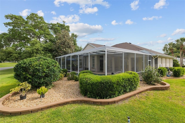 rear view of house featuring a lawn and glass enclosure
