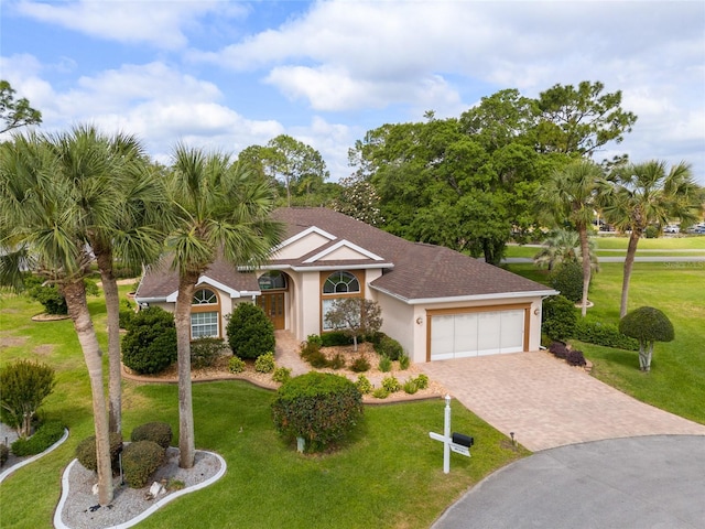 view of front facade with a front yard, stucco siding, driveway, and an attached garage