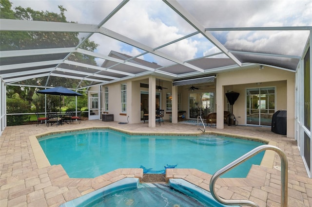 view of swimming pool with ceiling fan, a patio, glass enclosure, and a pool with connected hot tub