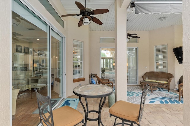 sunroom / solarium with ceiling fan and brick floor