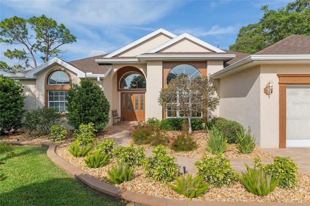 view of exterior entry with a shingled roof, stucco siding, concrete driveway, and an attached garage