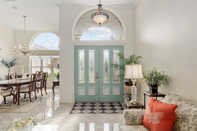 foyer featuring ornamental molding, an inviting chandelier, and french doors