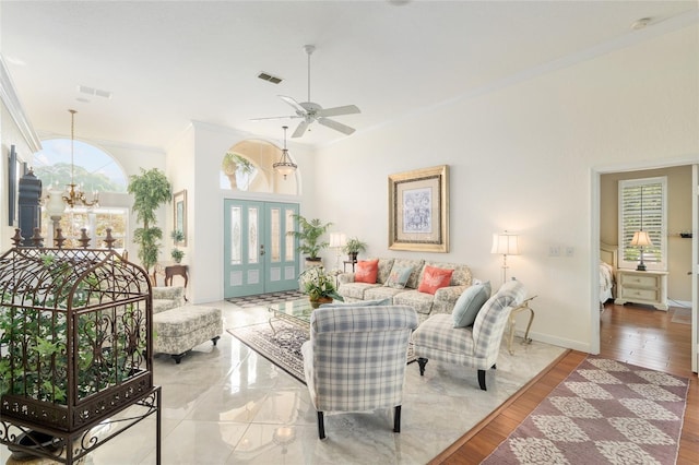 living room featuring ornamental molding, visible vents, french doors, and ceiling fan with notable chandelier