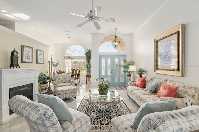 living room featuring ornamental molding, ceiling fan with notable chandelier, and a glass covered fireplace