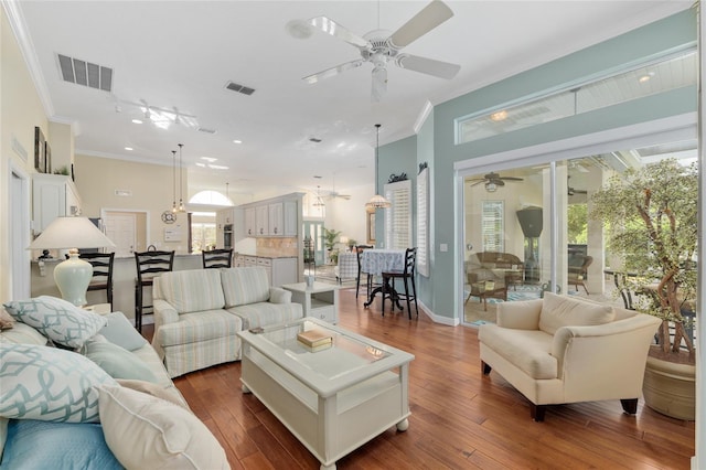 living room featuring dark wood finished floors, visible vents, a ceiling fan, and crown molding