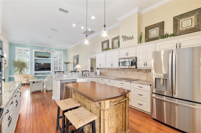kitchen with appliances with stainless steel finishes, a peninsula, and crown molding