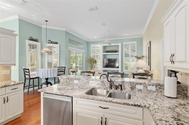 kitchen featuring a sink, ornamental molding, light wood-type flooring, visible vents, and stainless steel dishwasher