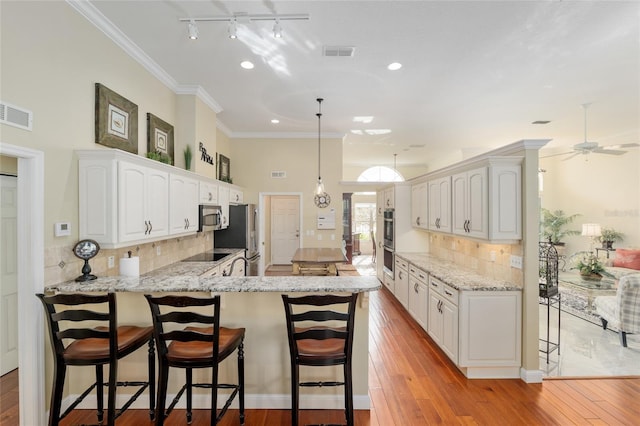 kitchen featuring a kitchen bar, visible vents, a peninsula, and stainless steel appliances