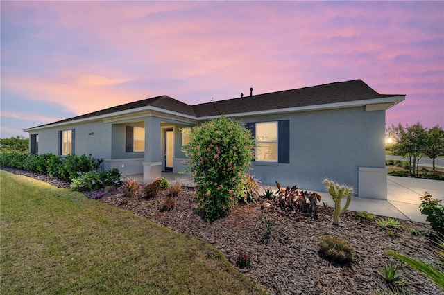 ranch-style home featuring stucco siding and a yard