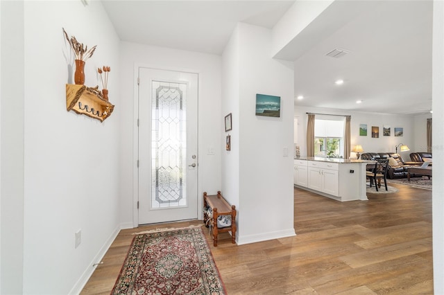 foyer featuring light wood finished floors, recessed lighting, and baseboards