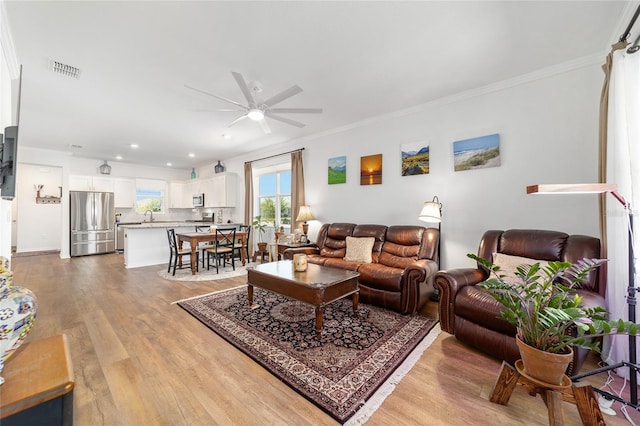 living area featuring ceiling fan, light wood-type flooring, crown molding, and recessed lighting
