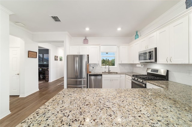 kitchen with stainless steel appliances, a sink, light stone counters, ornamental molding, and baseboards