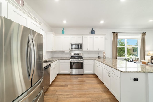 kitchen featuring stainless steel appliances, a peninsula, light wood-style floors, white cabinetry, and recessed lighting