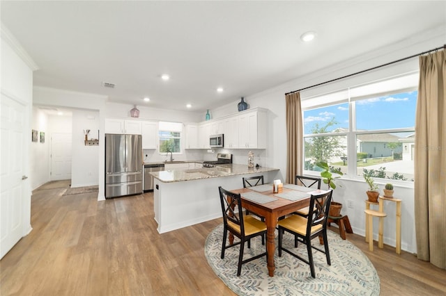 dining room with light wood-type flooring, recessed lighting, and ornamental molding