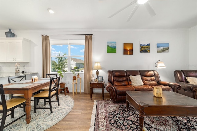 living room with light wood finished floors, ornamental molding, and ceiling fan