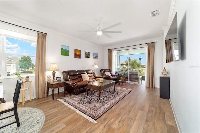 living area with crown molding, ceiling fan, light wood finished floors, and baseboards