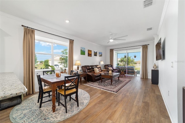 dining area with crown molding, ceiling fan, light wood finished floors, healthy amount of natural light, and baseboards