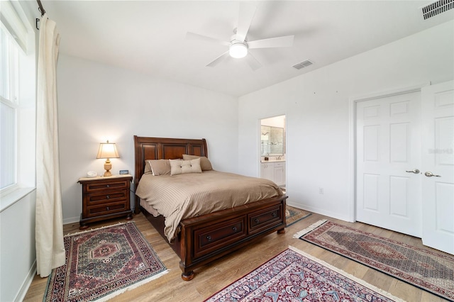 bedroom featuring wood finished floors, baseboards, ensuite bath, and a ceiling fan