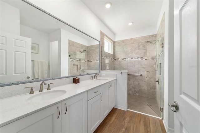 bathroom with a stall shower, wood finished floors, double vanity, and recessed lighting