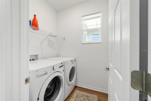 clothes washing area featuring washer and clothes dryer, baseboards, and dark wood-type flooring