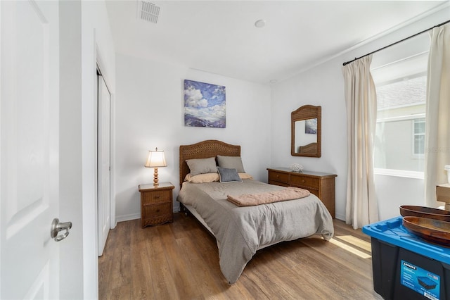 bedroom with wood finished floors, a closet, and baseboards