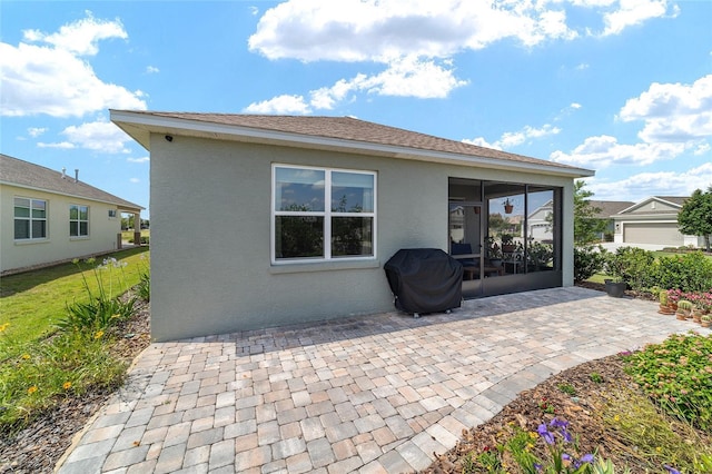 rear view of house featuring stucco siding, a patio area, and a sunroom