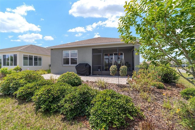 back of property with a sunroom, stucco siding, and a patio