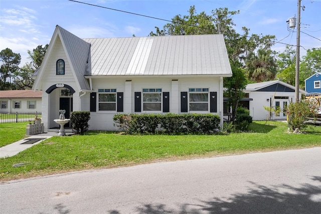 view of front of home featuring fence, metal roof, french doors, and a front lawn