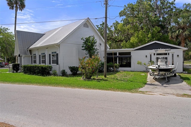 view of front of house featuring a front lawn, metal roof, and concrete driveway