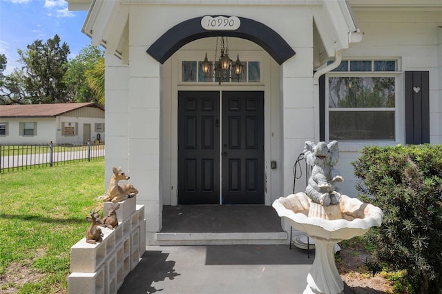 property entrance with fence and a yard