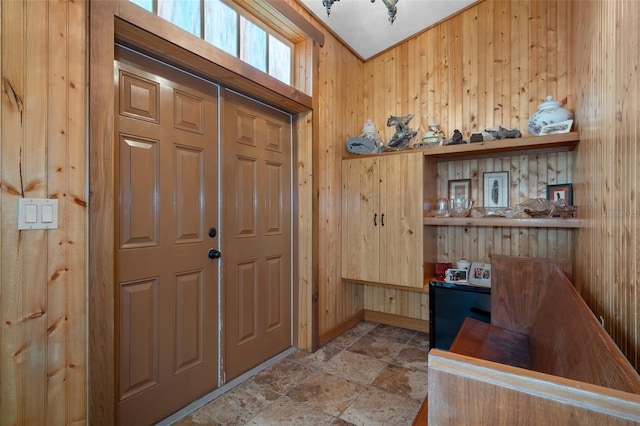 foyer with wood walls and stone finish flooring