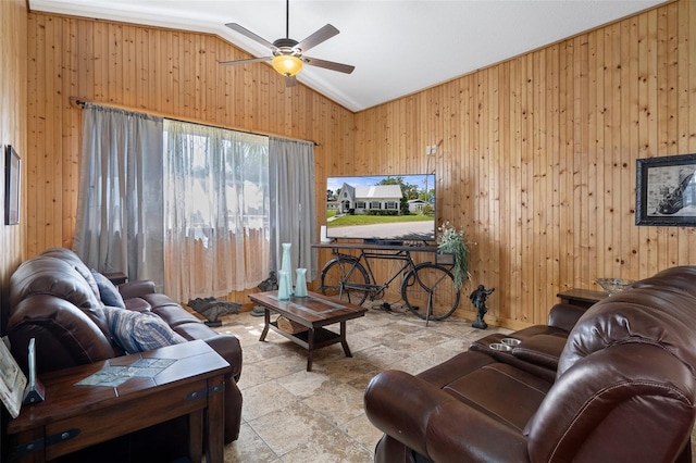 living room featuring lofted ceiling, stone finish floor, ceiling fan, and wood walls