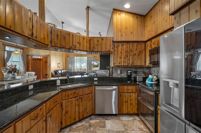 kitchen featuring dark stone countertops, decorative backsplash, appliances with stainless steel finishes, brown cabinets, and a sink