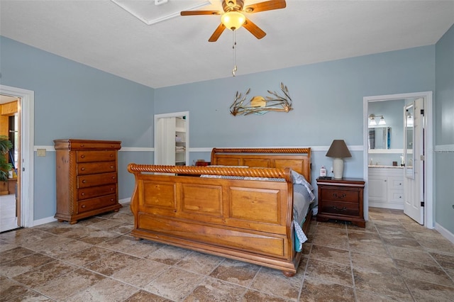 bedroom featuring stone finish flooring, connected bathroom, a ceiling fan, and baseboards