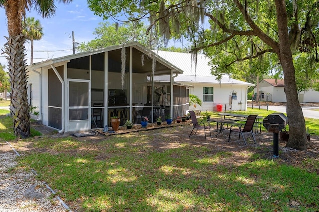 rear view of property with a sunroom and a lawn