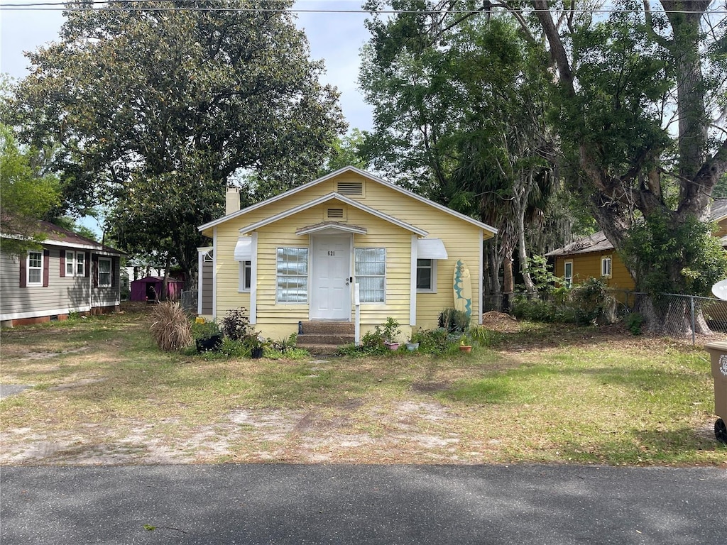 bungalow-style home with a front lawn, fence, and a chimney