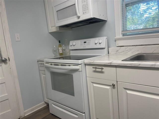621 NE 20th St, Ocala, FL 34470 - kitchen featuring white appliances, light countertops, dark wood-style flooring, white cabinetry, and baseboards