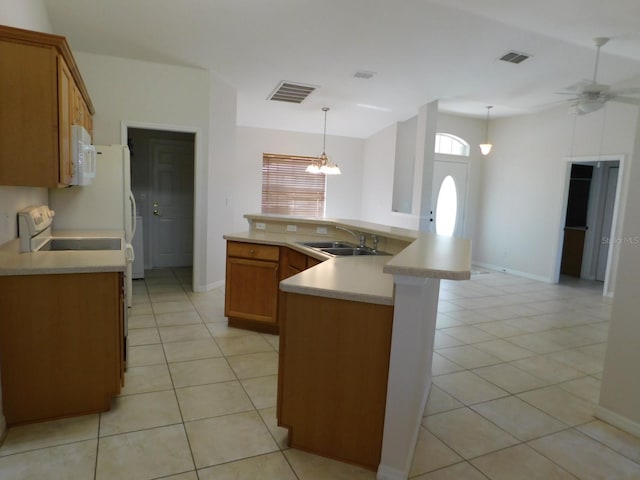 kitchen with a sink, white appliances, brown cabinets, and visible vents