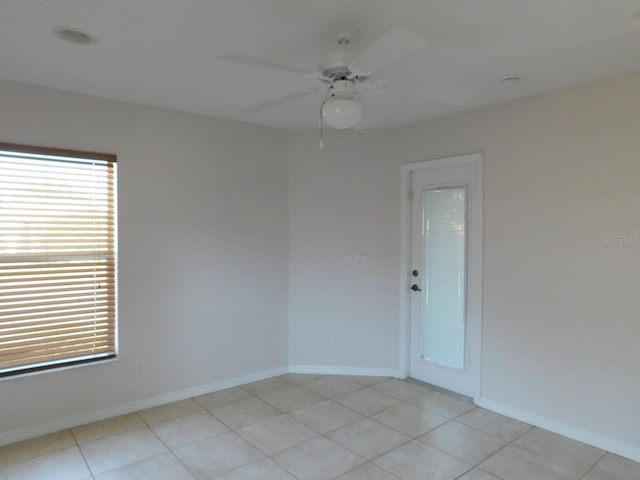 spare room featuring baseboards, light tile patterned floors, and ceiling fan
