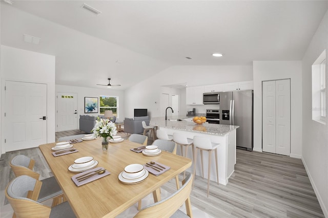 dining space with light wood-style floors, baseboards, visible vents, a ceiling fan, and lofted ceiling
