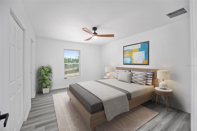 bedroom with visible vents, light wood-type flooring, a ceiling fan, and baseboards