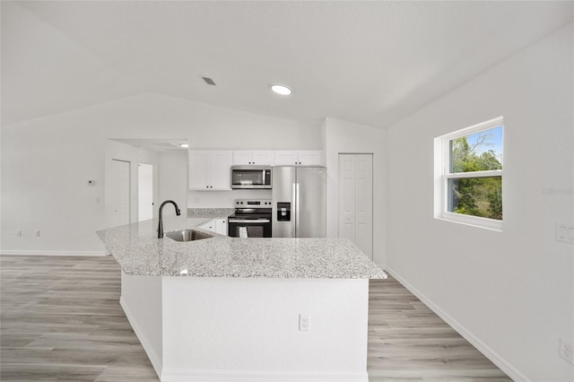 kitchen with light stone counters, appliances with stainless steel finishes, vaulted ceiling, a sink, and baseboards