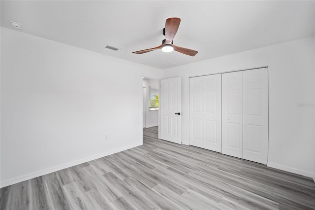 unfurnished bedroom featuring baseboards, visible vents, light wood-style floors, and a closet
