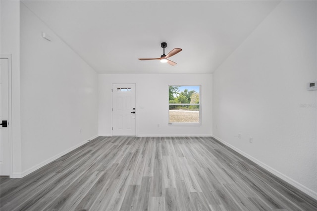 unfurnished living room featuring ceiling fan, light wood finished floors, vaulted ceiling, and baseboards
