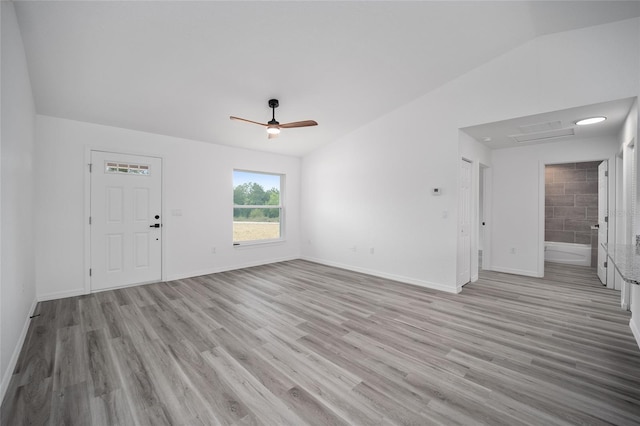 unfurnished living room with a ceiling fan, light wood-style flooring, vaulted ceiling, and baseboards